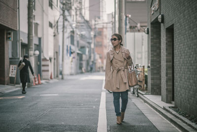 Full length of woman walking on footpath in city