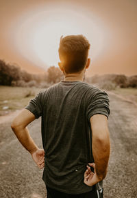 Rear view of man standing against sky during sunset