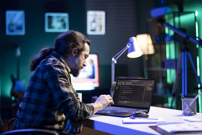 Rear view of man using mobile phone while sitting on table