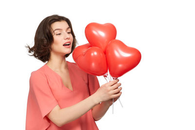 Close-up of a young woman holding heart shape over white background