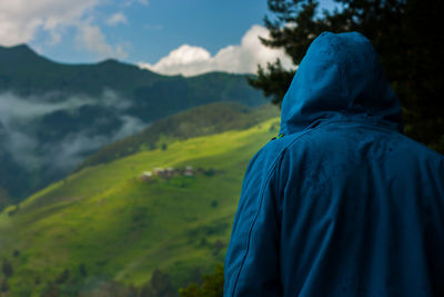 Rear view of person wearing hooded clothing against mountains