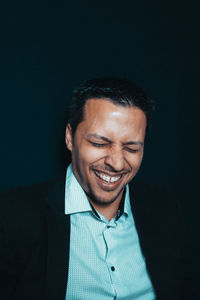 Portrait of a smiling young man against black background