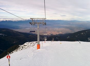 Overhead cable car over snowcapped mountains against sky