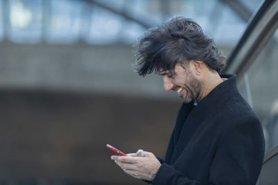 Side view of young man using mobile phone