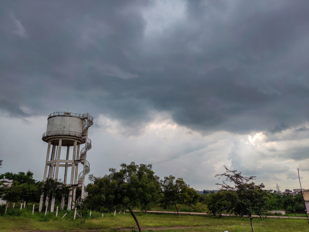 cloud, sky, tower, water tower, nature, storm, plant, environment, architecture, built structure, storm cloud, tree, wind, outdoors, no people, overcast, water tower - storage tank, rural area, grass, protection, building exterior, dramatic sky