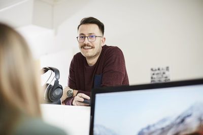 Smiling businessman looking at female coworker in office