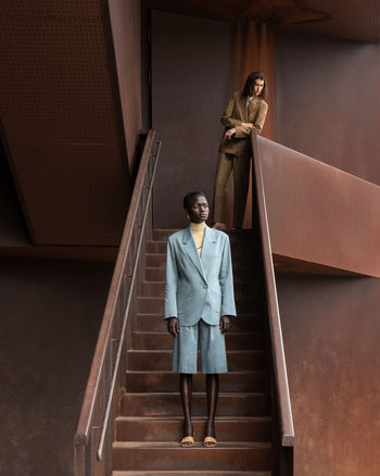 PORTRAIT OF WOMAN STANDING AGAINST STAIRCASE