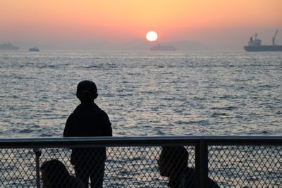 Silhouette family by sea during sunset