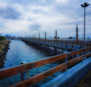 Pier over river against sky in city