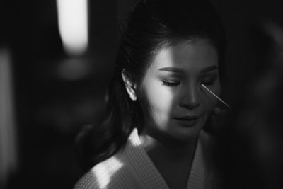 Close-up of young woman having make-up done