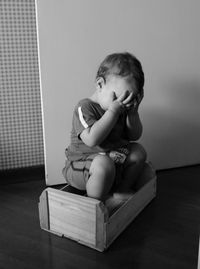 Cute boy sitting on wooden at home