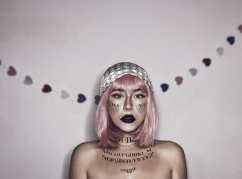 Portrait of young woman against wall