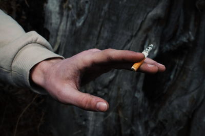 Hand that holds a cigarette in the forest