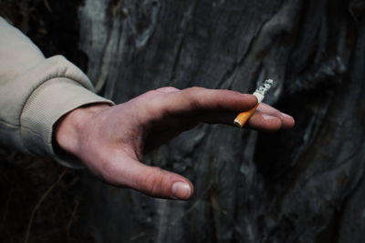 Midsection of person holding cigarette