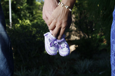 Cropped image of couple holding purple baby booties