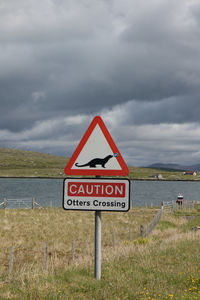 Road sign by sea against sky