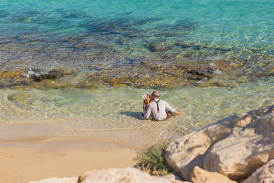 Man sitting on rock at sea shore