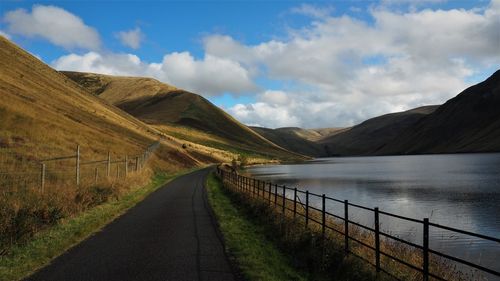 Scenic view of road by mountains against sky