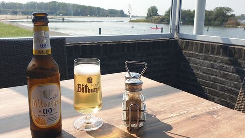 Glass of bottles on table by sea