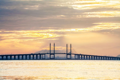 Bridge over river against cloudy sky