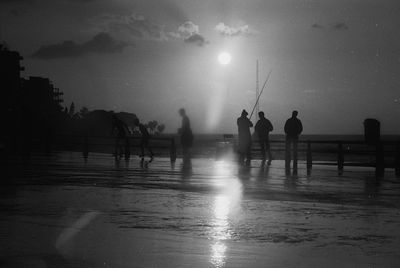 Silhouette people on beach against sky during rainy season