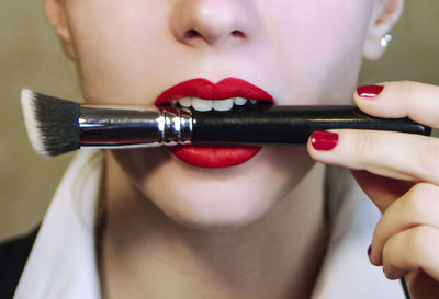 Cropped image of woman biting make-up brush