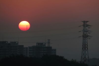 Low angle view of electricity pylon at sunset