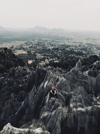 High angle view of man sitting on rock against sky