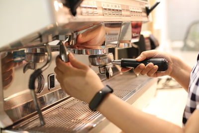 Midsection of woman using coffee streamer machine