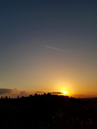 Silhouette vapor trail against sky during sunset