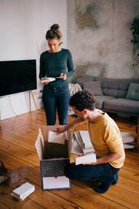 Couple removing novels from box in living room at new home