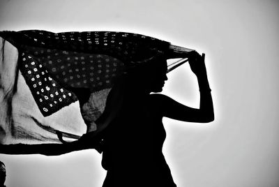  woman standing against white background with flowing scarf in the wind