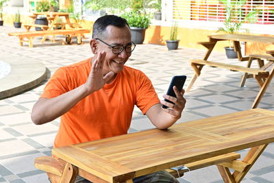 Man using mobile phone while sitting on table