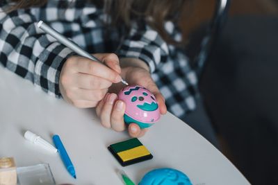Midsection of girl coloring easter egg on table