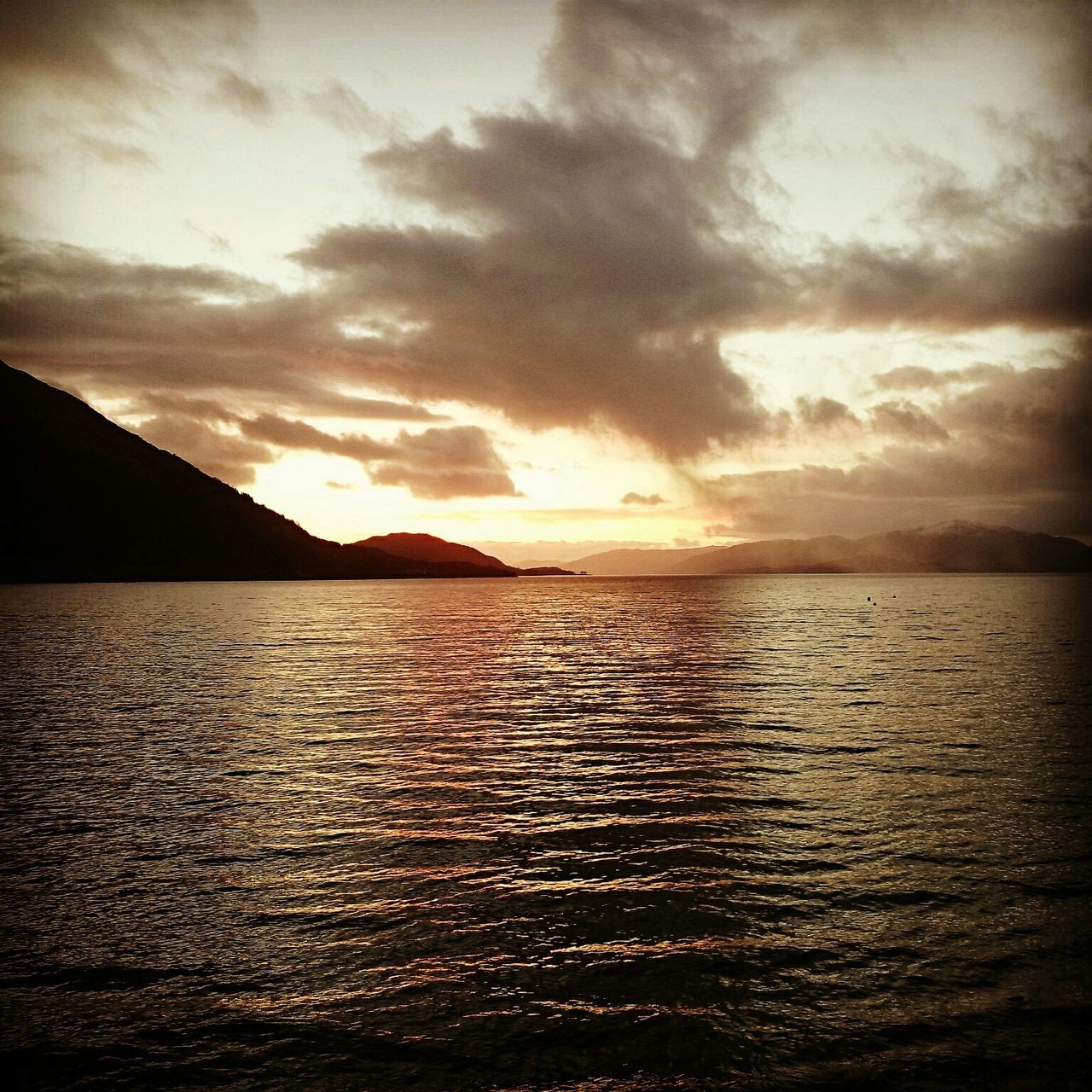 water, tranquil scene, scenics, sea, sunset, beauty in nature, tranquility, sky, waterfront, nature, rippled, cloud - sky, idyllic, horizon over water, cloud, mountain, silhouette, orange color, cloudy, outdoors