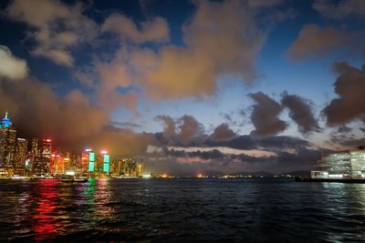 Illuminated city against cloudy sky