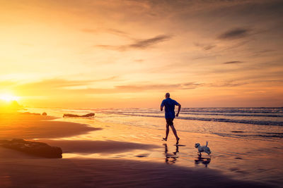 People on beach against sky during sunset