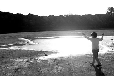 Rear view of little boy walking towards small pond