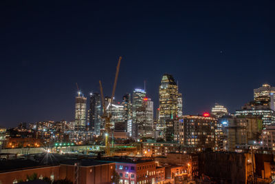 Illuminated buildings in city against sky at night