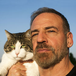 Portrait of man with cat against sky