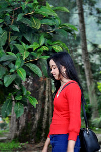 Woman standing by tree in forest