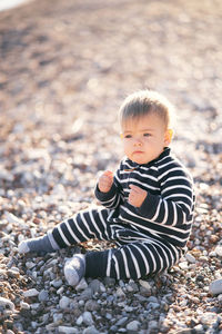 Cute boy sitting on pebbles