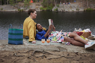 Female couple having picnic and reading book