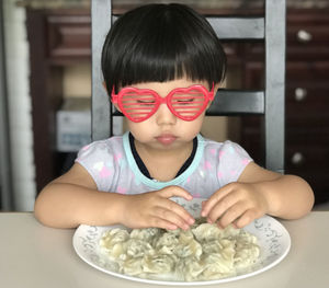 Cute girl wearing sunglasses eating food at home