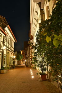 Illuminated street amidst buildings at night