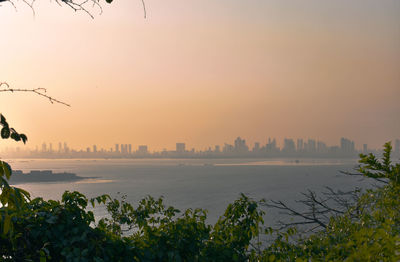 Scenic view of sea and buildings against sky during sunset