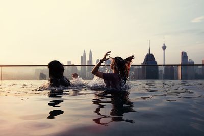 Women swimming in infinity pool during sunset