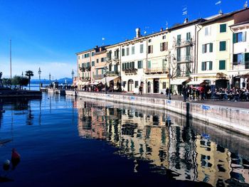 Buildings by canal against blue sky