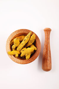 Close-up of turmeric with mortar and pestle over white background