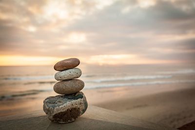 Stack of pebbles on beach against sky during sunset